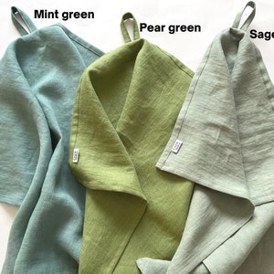 K&ouml;nnte beinhalten: Drei K&uuml;chent&uuml;cher in Minzgr&uuml;n, Birnengr&uuml;n und Salbeigr&uuml;n. Jedes Tuch hat oben eine Schlaufe zum Aufh&auml;ngen und ein kleines wei&szlig;es Markenetikett an der Seite. Der Text Mint green, Pear green und Sage green steht jeweils &uuml;ber den T&uuml;chern.