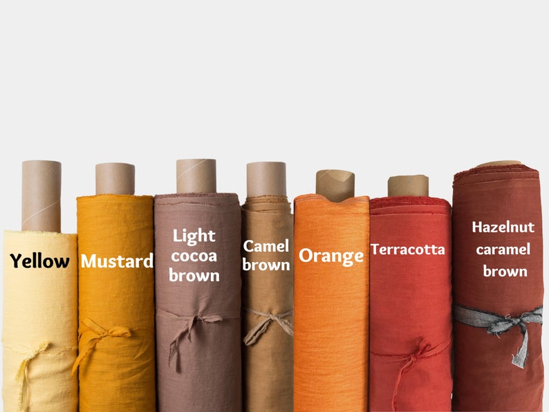 May include: Eight rolls of fabric in various shades of yellow, orange, and brown. The fabric rolls are labeled with the colors: Yellow, Mustard, Light cocoa brown, Camel brown, Orange, Terracotta, Hazelnut caramel brown.