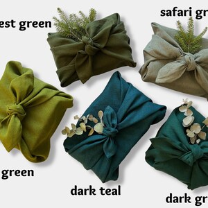 May include: Five fabric gift wraps in different shades of green, including forest green, safari green, moss green, dark teal, and dark green. Each wrap is tied with a knot and decorated with a sprig of greenery.