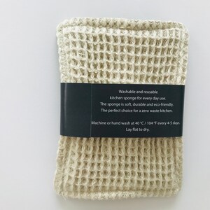 May include: A beige waffle-weave kitchen sponge with a black label that reads "Washable and reusable kitchen sponge for every day use. The sponge is soft, durable and eco-friendly. The perfect choice for a zero waste kitchen. Machine or hand wash at 40 &deg;C / 104 &deg;F every 4-5 days. Lay flat to dry."