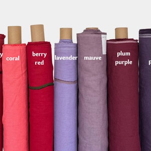 May include: Eight rolls of fabric in various shades of pink, red, purple, and lavender. The fabric is labeled with the colors: raspberry pink, coral, berry red, lavender, mauve, plum purple, and dark purple.