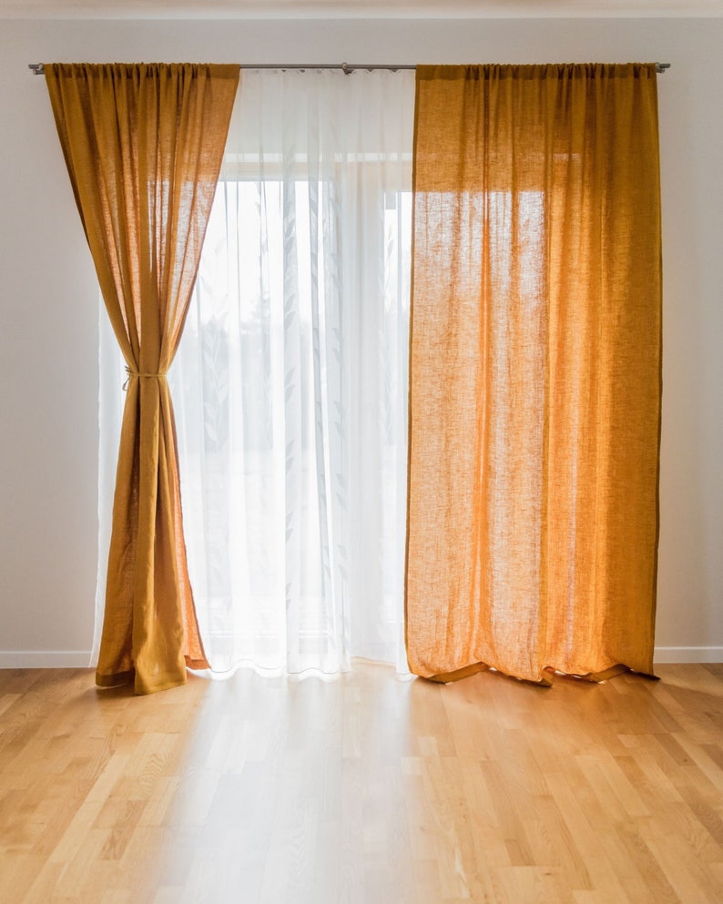 K&ouml;nnte beinhalten: Ein Fenster mit zwei Gardinen. Ein Satz ist aus wei&szlig;en, durchsichtigen Gardinen und der andere aus senfgelben Leinenvorh&auml;ngen. Die Gardinen sind zugezogen und das Fenster l&auml;sst nat&uuml;rliches Licht herein.