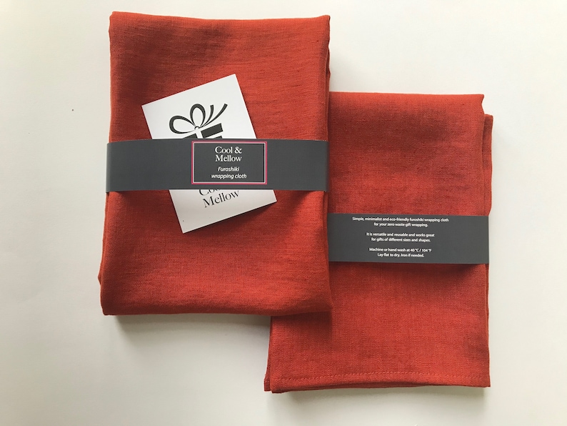 May include: Two rust-colored fabric squares, folded and stacked. The top square has a black label that reads "Cool & Mellow" and "Furoshiki wrapping cloth".