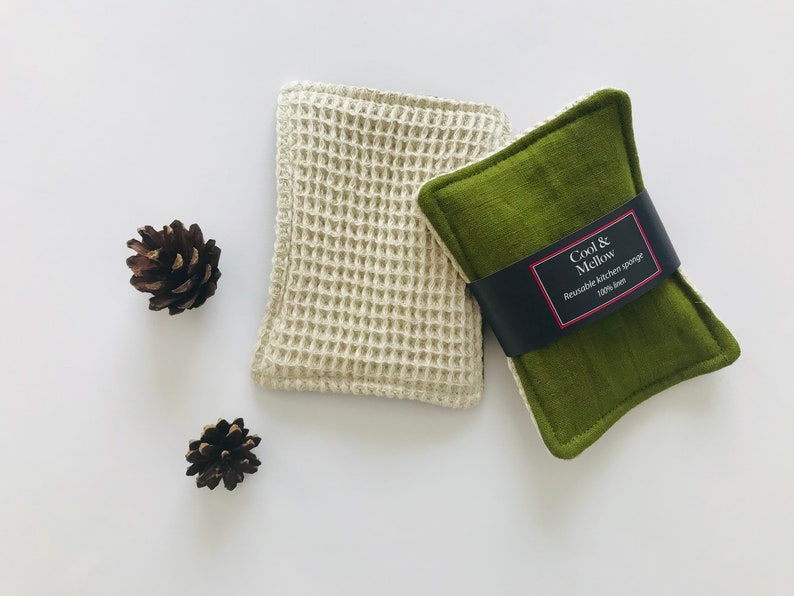 May include: Two reusable kitchen sponges, one white waffle weave and one green, with a black label that reads "Cool & Mellow Reusable kitchen sponge 100% flax"
