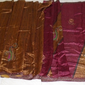 May include: A draped textile featuring sections of brown and burgundy fabric. The brown section has vertical lines and a paisley design. The burgundy section has a paisley design and a gold-colored stripe. The edges are trimmed with a decorative border.