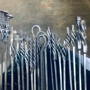 May include: A collection of 15 metal fireplace tools with various decorative designs, including twisted, looped, and cross-shaped handles. The tools are arranged vertically and are all silver in color.
