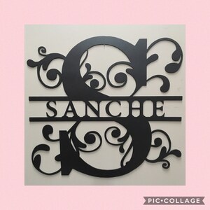 May include: Black metal wall decor featuring a large letter "S" with decorative flourishes and the name "SANCHE" centred below.