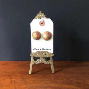 May include: A pair of round, colorful, mosaic-style earrings on a white tag with the text "Hart & Modern".