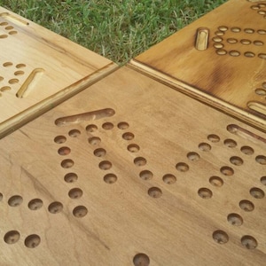 May include: Four wooden game boards with circular holes and carved lines. The boards are made of light brown wood and have a natural finish.