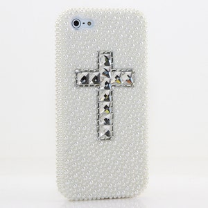 May include: White iPhone case covered in small white pearls with a large silver rhinestone cross in the center.