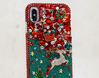 Op de afbeelding: Een groene en rode telefoonhoes met strass, een rendier, een kerstboom en andere feestelijke decoraties.