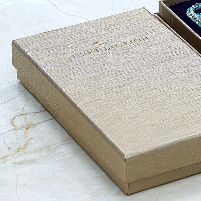 May include: A beige box with the text "LUXADDICTION" embossed on the top.