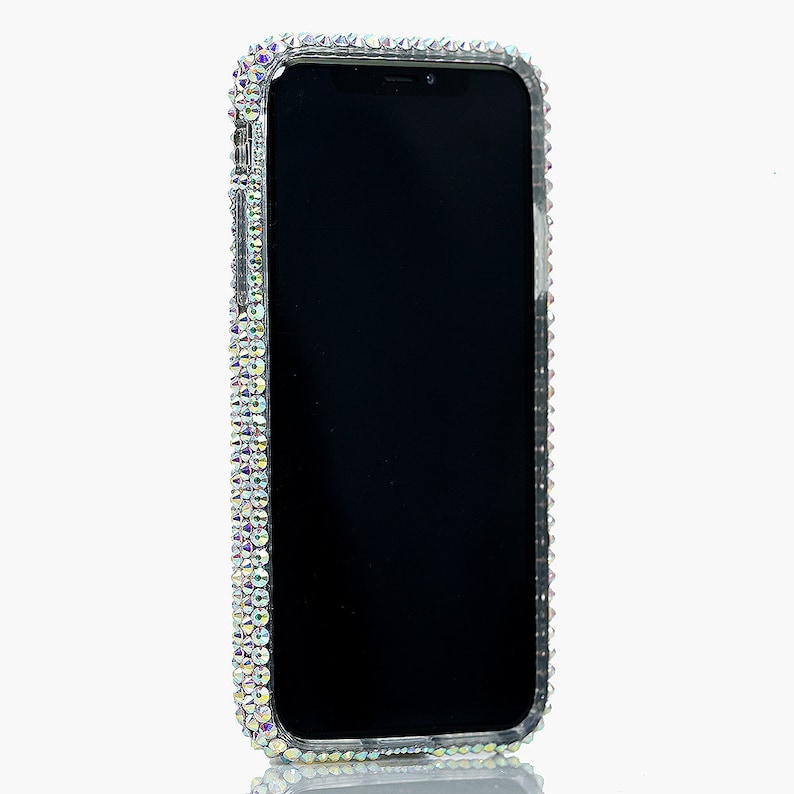 May include: A clear phone case with a black phone inside. The case is covered in iridescent rhinestones.
