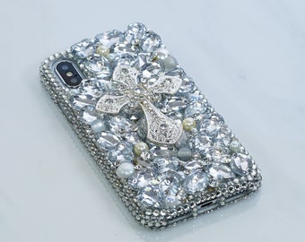 Peut inclure: Une coque de téléphone argentée avec un grand motif de croix argentée, recouverte de strass transparents et blancs.
