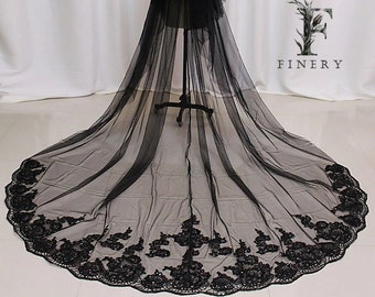May include: A long black tulle wedding veil with a scalloped edge and black floral embroidery. The veil is displayed on a mannequin.