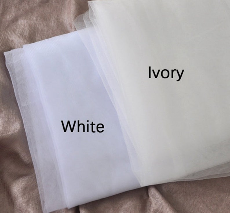 May include: Two swatches of tulle fabric, one white and one ivory. The fabric is soft and sheer, and the colors are subtle.