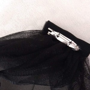 May include: Black tulle fabric with a silver metal clip attached to the edge.