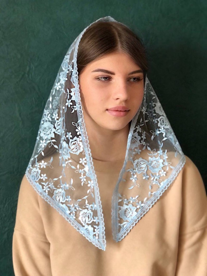 Puede incluir: Un velo de encaje azul claro con bordados florales. El velo est&aacute; doblado en forma triangular y tiene un borde festoneado.