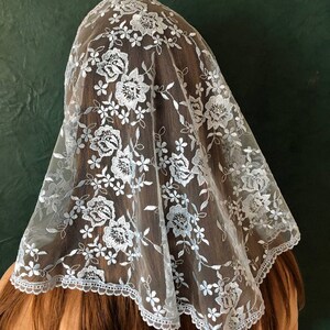 Puede incluir: Un velo de encaje azul claro con un patr&oacute;n floral. El velo tiene un borde festoneado y est&aacute; hecho de una tela transparente.