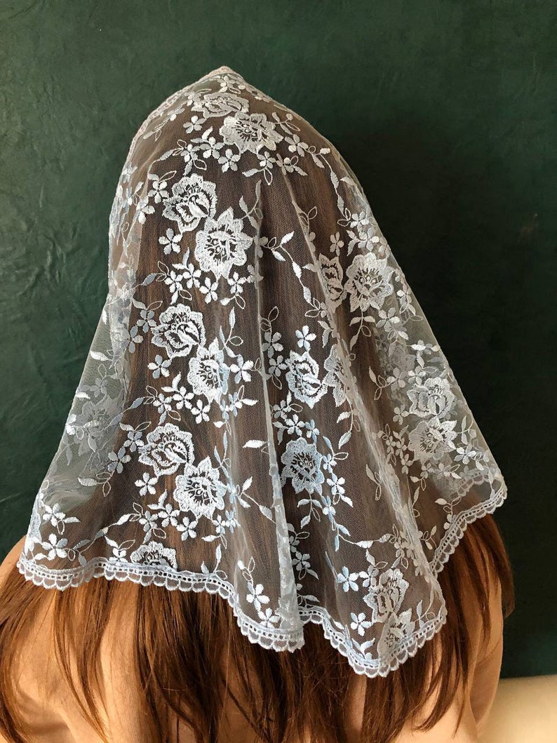 Puede incluir: Un velo de encaje azul claro con un patr&oacute;n floral. El velo tiene un borde festoneado y est&aacute; hecho de una tela transparente.