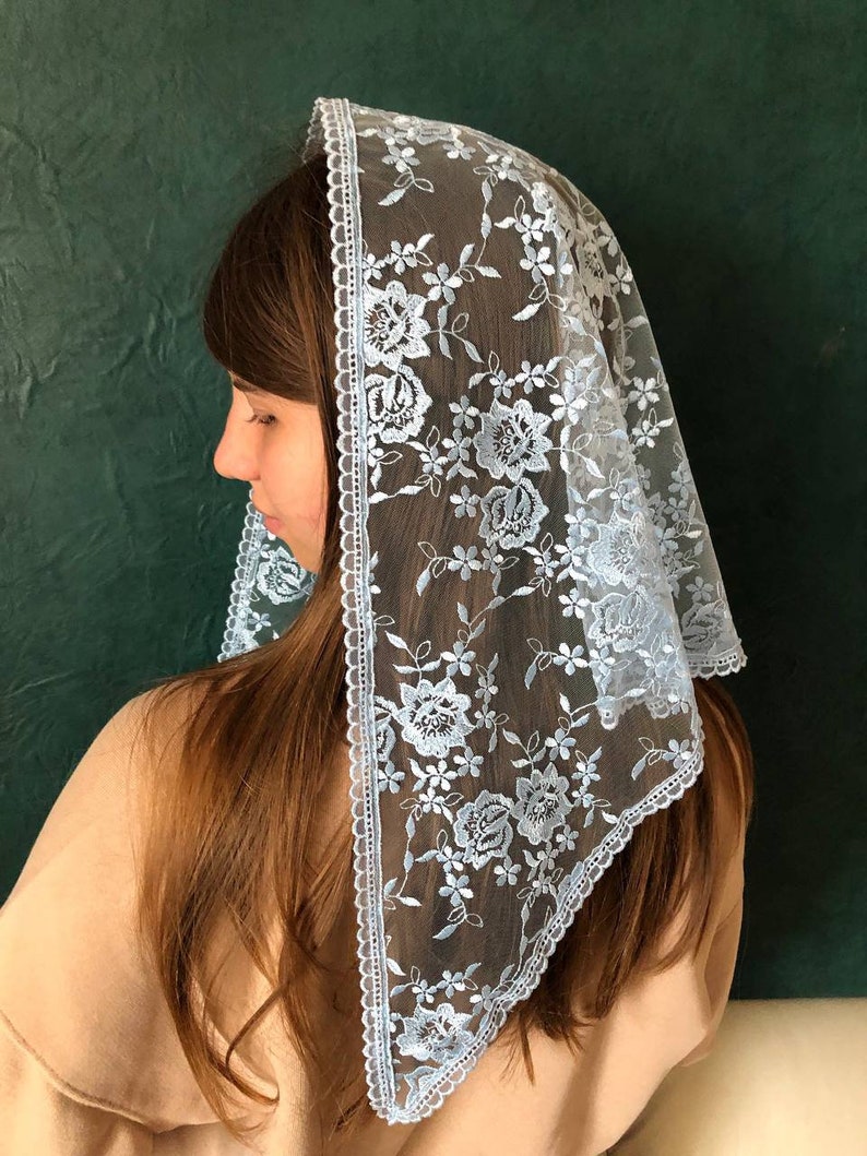 Puede incluir: Un velo de encaje azul claro con un patr&oacute;n floral. El velo est&aacute; adornado con un borde blanco festoneado.