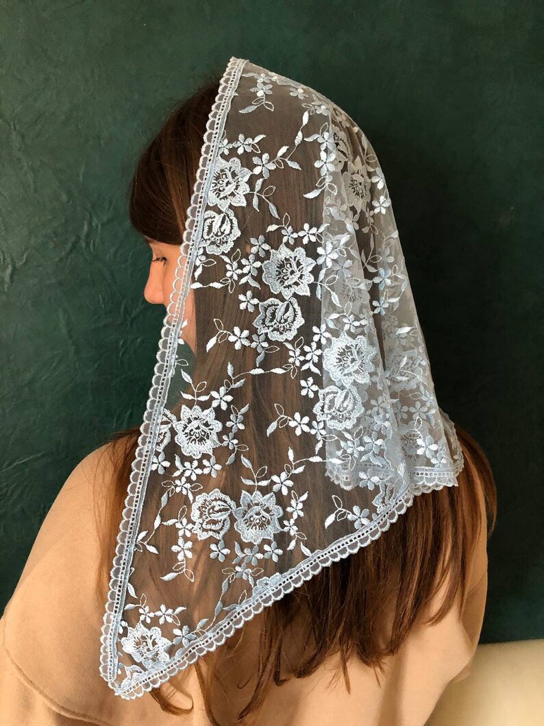 Puede incluir: Un velo de encaje azul claro con un patr&oacute;n floral. El velo est&aacute; adornado con un borde festoneado.