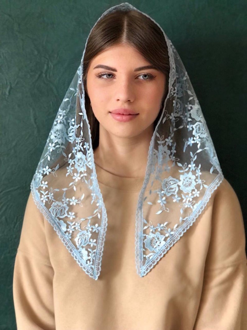 Puede incluir: Un velo de encaje azul claro con bordados florales. El encaje es delicado y tiene un borde festoneado.