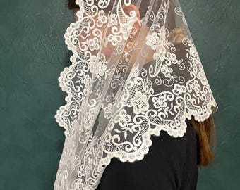 May include: White lace mantilla with a floral design. The lace is delicate and intricate, and the mantilla is perfect for a special occasion.