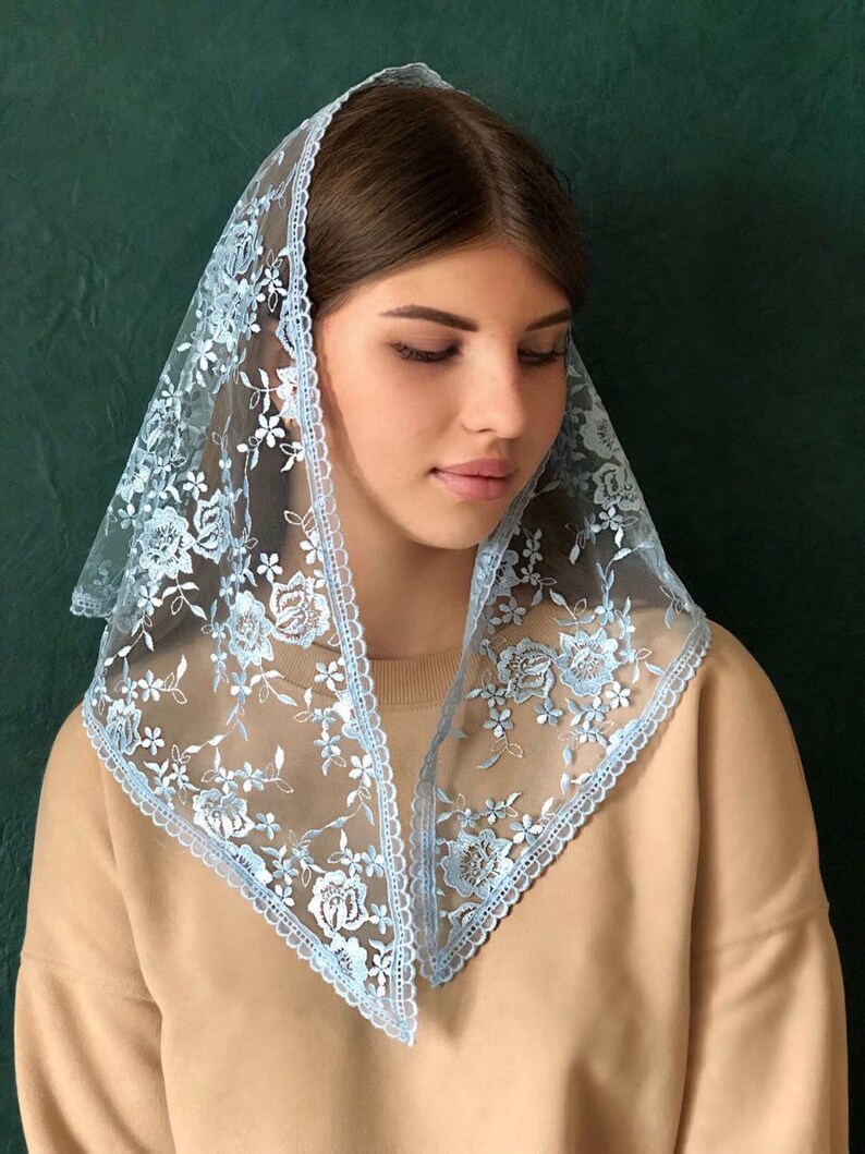 Puede incluir: Un velo de encaje azul claro con bordados florales. El velo est&aacute; doblado en forma triangular y tiene un borde festoneado.