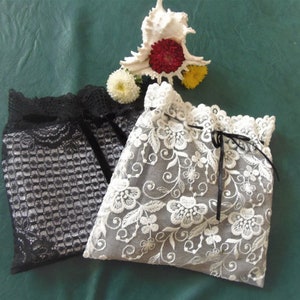 Puede incluir: Dos bolsas delicadas de encaje, una negra y otra blanca con bordados florales. Ambas bolsas tienen un cierre de cord&oacute;n.