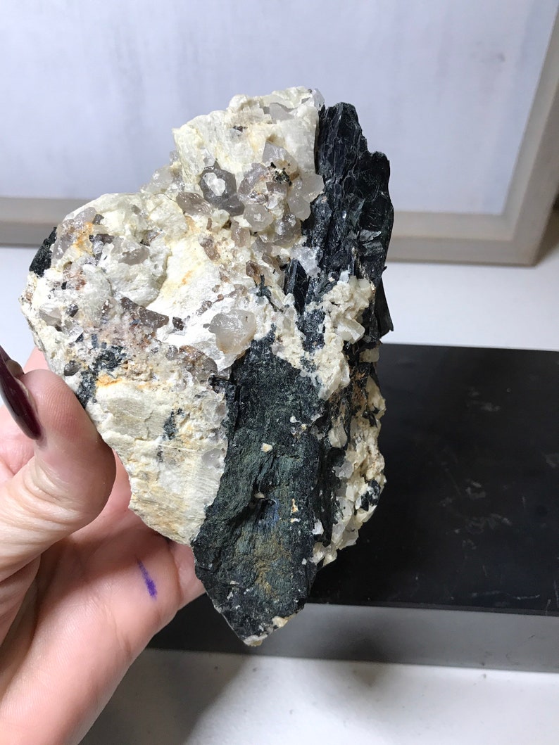 May include: A rough, gray and black rock with a cluster of clear quartz crystals embedded in it. The rock has a natural, unpolished look.