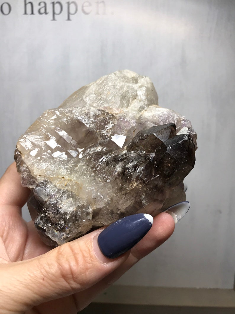 May include: A large, clear quartz crystal with smoky quartz inclusions. The crystal has a natural, rough texture and is a beautiful example of the mineral.