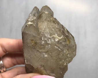 May include: A clear quartz crystal with a double termination. The crystal has a natural, raw appearance with some inclusions.