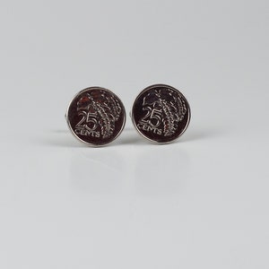Pode incluir: Dois botões de punho de prata com um design de moeda de 25 cêntimos. As moedas apresentam uma imagem castanha de uma planta com as palavras "25 CENTS" impressas nelas.