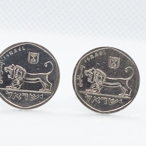 May include: Two silver Israeli coins with a lion and the word "ISRAEL" on them.