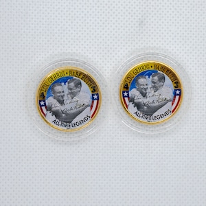 May include: Two gold-colored commemorative coins featuring Lou Gehrig and Babe Ruth. The coins have a clear plastic casing and include the text "LOU GEHRIG BABE RUTH ALL-TIME LEGENDS" and signatures.