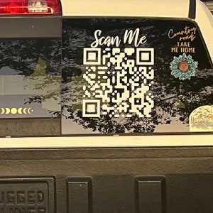 Peut inclure: Un autocollant blanc sur une vitre de v&eacute;hicule pr&eacute;sente un grand code QR avec le texte "Scan Me". Le texte "Country Roads Take Me Home" est &eacute;galement pr&eacute;sent, avec un motif floral. Une s&eacute;rie d'autocollants de phases lunaires est &eacute;galement visible.