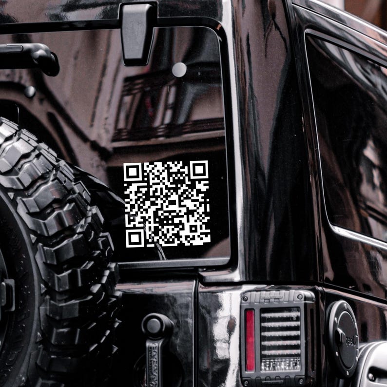 Peut inclure: Un autocollant de code QR blanc est appos&eacute; sur la vitre arri&egrave;re d'un v&eacute;hicule noir. L'autocollant est rectangulaire et pr&eacute;sente un motif complexe de carr&eacute;s noirs et blancs. Le pneu et le feu arri&egrave;re du v&eacute;hicule sont &eacute;galement visibles.