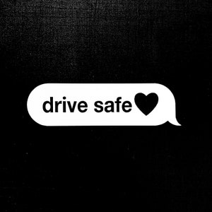 Può includere: Una bolla di messaggio di testo bianca con il testo "drive safe" e un'icona di cuore nero.