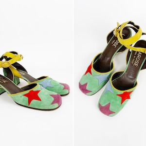 May include: A pair of green suede heeled shoes with a yellow ankle strap and multi-colored star accents. The shoes are labeled "Arose Made in Italy".