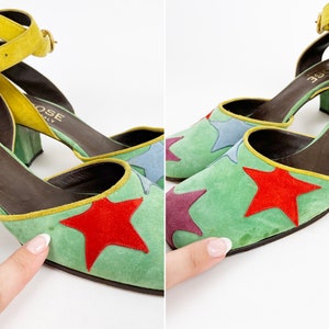 May include: A pair of green suede heeled shoes with a yellow ankle strap. The shoes have a star pattern with red, blue, and purple stars. The shoes are labeled "LAROSE ITALY".