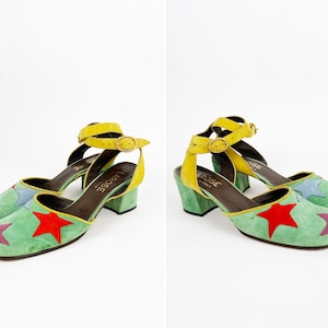 May include: A pair of green suede heeled shoes with a yellow ankle strap and multi-colored star accents. The shoes are labeled "La Rose" on the insole.
