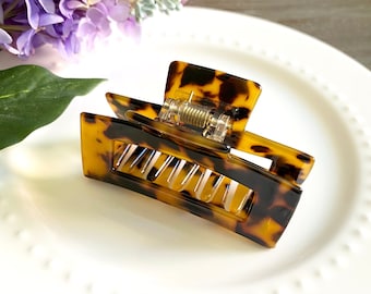 May include: A brown and black tortoiseshell hair claw with a spring-loaded clasp.