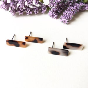 Puede incluir: Tres pares de pendientes rectangulares de carey. Los pendientes están hechos de un material estampado marrón y negro.