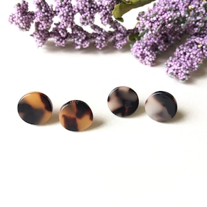 May include: Three pairs of round, brown and white patterned earrings. The earrings are made of a tortoiseshell-like material.