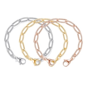 May include: Three chain link bracelets in silver, gold, and rose gold. Each bracelet features an oval link design and a lobster clasp closure. The bracelets are displayed against a white background.