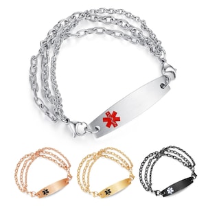 Könnte beinhalten: Ein silbernes medizinische ID-Armband mit einem roten Sternsymbol. Das Armband hat drei Kettenglieder und eine rechteckige Platte zum Gravieren. Zusätzliche Armbänder in Roségold, Gold und Schwarz sind ebenfalls abgebildet.