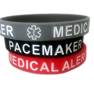May include: Three silicone medical alert bracelets. The top bracelet is gray with a white medical symbol and the text "MEDICAL ALERT". The middle bracelet is black with white text that says "PACEMAKER". The bottom bracelet is red with white text that says "MEDICAL ALERT".