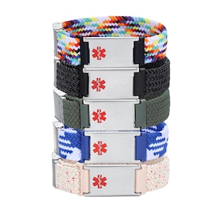 May include: Five medical alert bracelets stacked, each with a woven band in different colours: rainbow, black, olive green, blue and white, and speckled pink. Each has a silver-coloured metal plate with a red medical symbol.