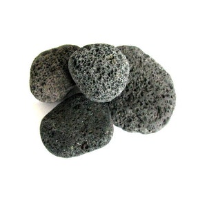 May include: Four dark gray, rough, and porous volcanic rocks, also known as lava rocks, on a white background.